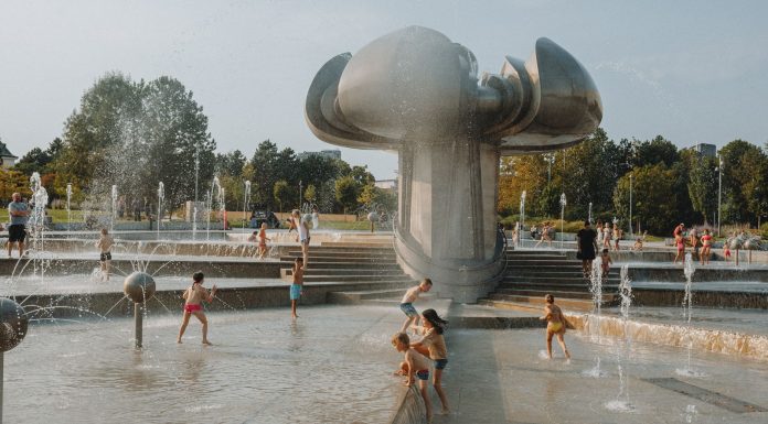 Happy children enjoy a sunny day playing in an urban fountain park with modern sculptures.