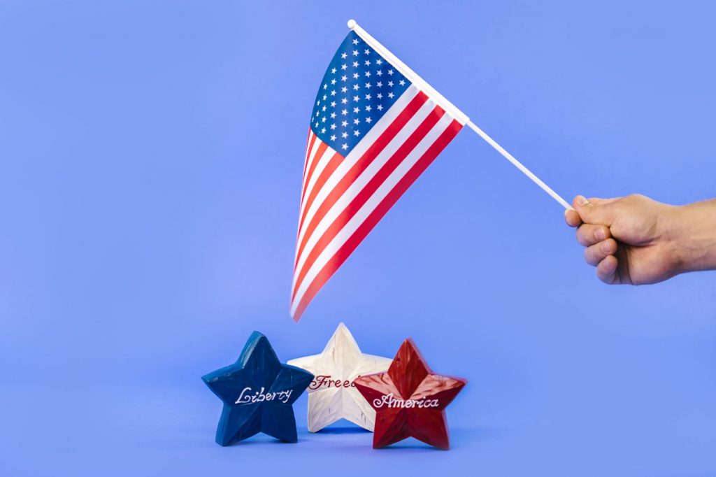 Hand holding American flag with red, white, and blue stars symbolizing liberty and freedom.