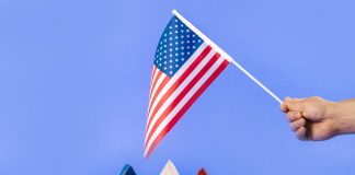 Hand holding American flag with red, white, and blue stars symbolizing liberty and freedom.
