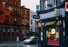 Busy urban street with Subway shop and historic architecture.