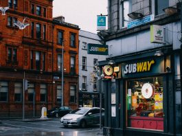 Busy urban street with Subway shop and historic architecture.