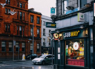 Busy urban street with Subway shop and historic architecture.