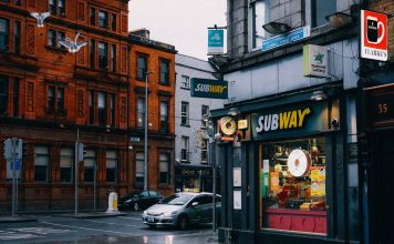 Busy urban street with Subway shop and historic architecture.