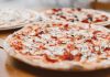 Close-up of freshly baked pizzas with mushrooms served on a wooden table.