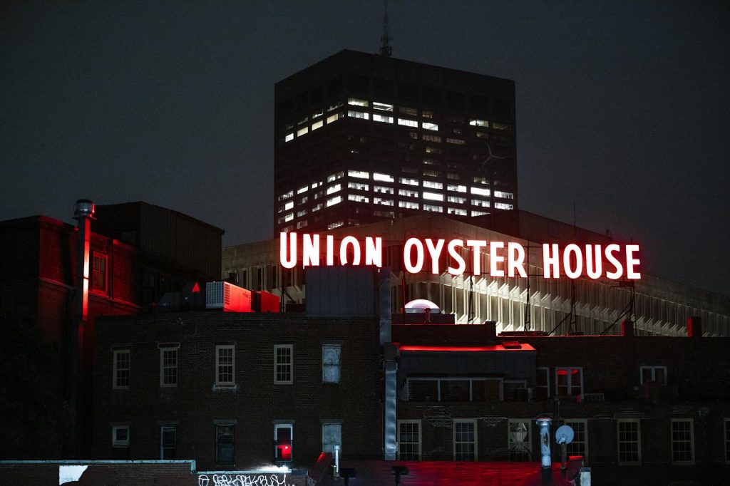 View of the illuminated Union Oyster House neon sign against a night sky in Boston.