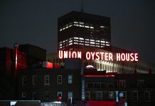 View of the illuminated Union Oyster House neon sign against a night sky in Boston.