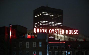 View of the illuminated Union Oyster House neon sign against a night sky in Boston.