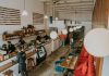 Bright and inviting coffee shop interior with people working, featuring stylish decor and pendant lighting.