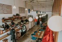 Bright and inviting coffee shop interior with people working, featuring stylish decor and pendant lighting.