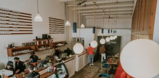 Bright and inviting coffee shop interior with people working, featuring stylish decor and pendant lighting.