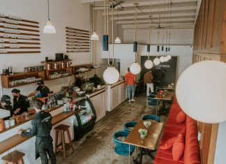 Bright and inviting coffee shop interior with people working, featuring stylish decor and pendant lighting.