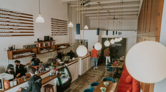 Bright and inviting coffee shop interior with people working, featuring stylish decor and pendant lighting.