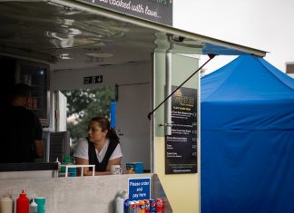 Descubre los Mejores Food Trucks en Newark, NJ: Guía 2026 para Amantes de la Comida Callejera A food truck with staff serving at an outdoor festival with colorful tents.