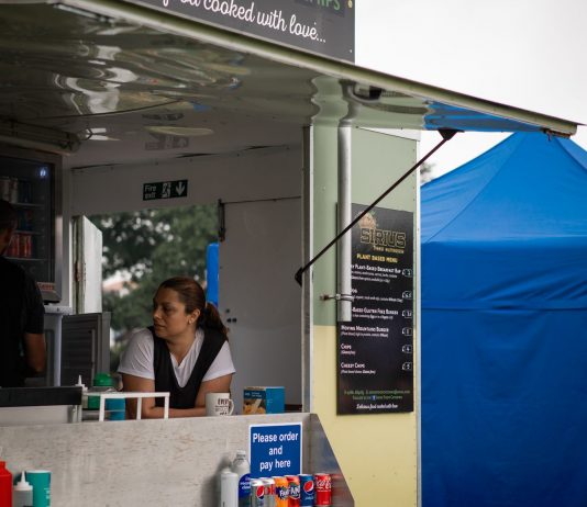 Descubre los Mejores Food Trucks en Newark, NJ: Guía 2026 para Amantes de la Comida Callejera A food truck with staff serving at an outdoor festival with colorful tents.