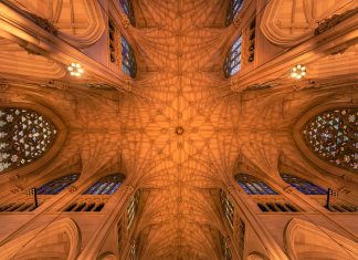 Intricate architecture and stained glass windows of St. Patrick's Cathedral ceiling in New York City.