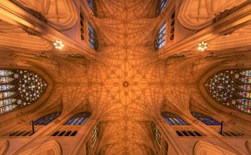 Intricate architecture and stained glass windows of St. Patrick's Cathedral ceiling in New York City.