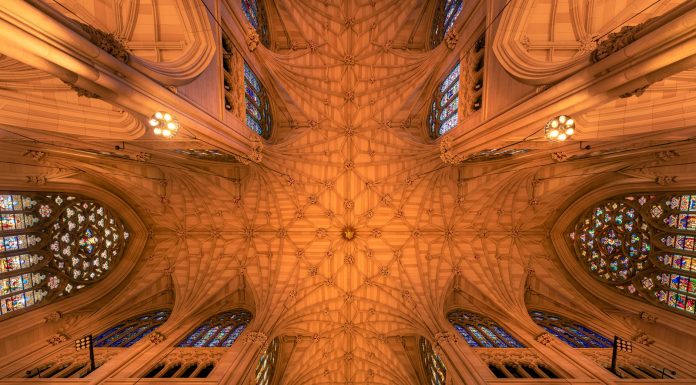 Intricate architecture and stained glass windows of St. Patrick's Cathedral ceiling in New York City.