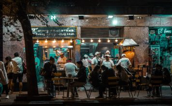 Los Mejores Restaurantes Abiertos Hasta Tarde en Hoboken: Guía 2026 para Comer de Noche Crowded urban street restaurant at night, capturing lively city nightlife and dining.