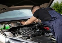 Auto mechanic performs engine maintenance on a car. Focus on hands and engine components.