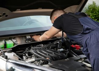 Auto mechanic performs engine maintenance on a car. Focus on hands and engine components.