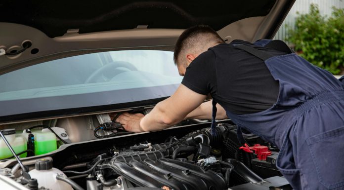 Auto mechanic performs engine maintenance on a car. Focus on hands and engine components.