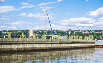 Mudarse a Bayonne: Todo Lo Que Necesitas Saber en 2026 Tranquil water reflection and wooden pier under a vibrant blue sky in Alpine, New Jersey.