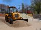 A yellow backhoe loader at a construction site moving sand on a clear day.