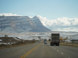A winter road trip through mountainous terrain with vehicles on a scenic highway.