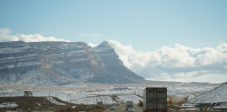 A winter road trip through mountainous terrain with vehicles on a scenic highway.