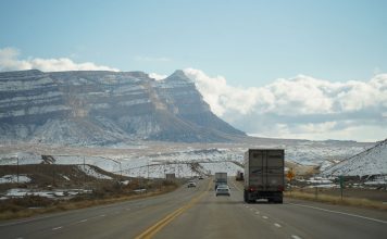 A winter road trip through mountainous terrain with vehicles on a scenic highway.