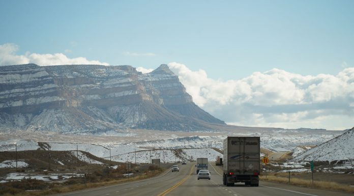 A winter road trip through mountainous terrain with vehicles on a scenic highway.