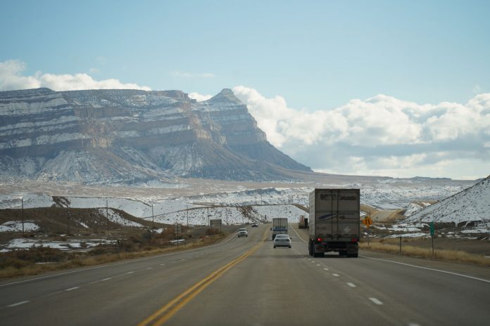 A winter road trip through mountainous terrain with vehicles on a scenic highway.
