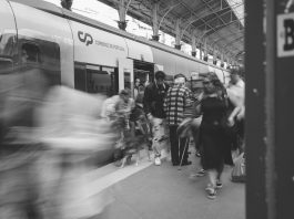 A black and white scene of commuters at a Lisbon train station, showcasing urban movement.