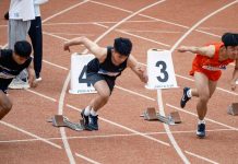 Young male sprinters launching off at the starting line, showcasing athletic determination on the track.
