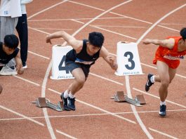 Young male sprinters launching off at the starting line, showcasing athletic determination on the track.