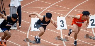Young male sprinters launching off at the starting line, showcasing athletic determination on the track.