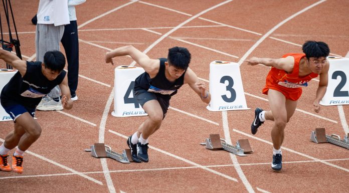 Young male sprinters launching off at the starting line, showcasing athletic determination on the track.