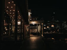 A stylish rooftop bar at night with a city skyline view and ambient lighting.