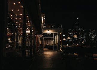A stylish rooftop bar at night with a city skyline view and ambient lighting.