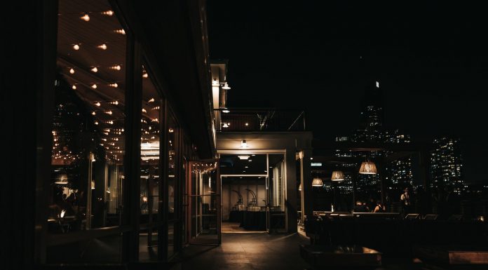 A stylish rooftop bar at night with a city skyline view and ambient lighting.