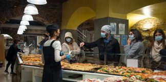 Shoppers wearing masks buy pizza slices from a bakery in Bergamo, Italy.