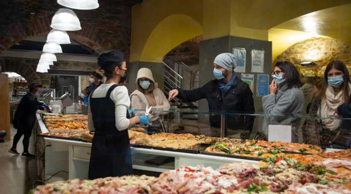 Shoppers wearing masks buy pizza slices from a bakery in Bergamo, Italy.