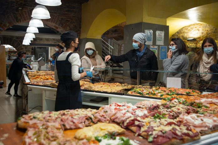 Shoppers wearing masks buy pizza slices from a bakery in Bergamo, Italy.