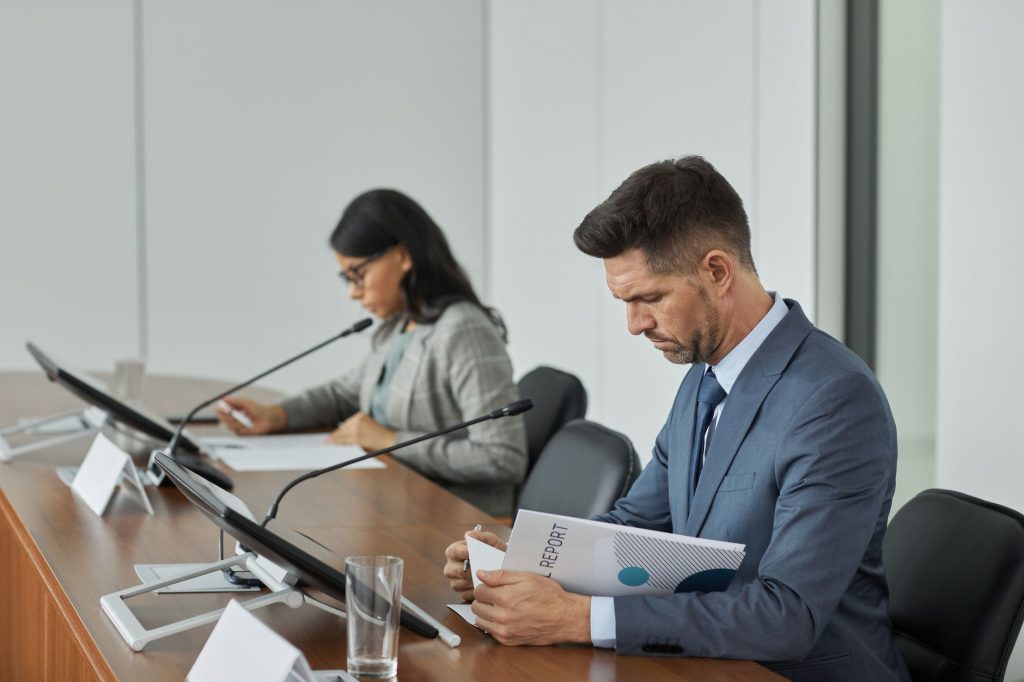 Business professionals in a conference setting, focusing on documents and reports.
