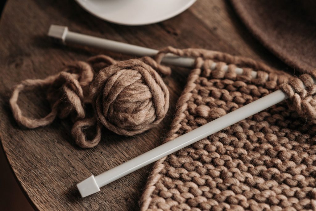 A close-up shot of cozy brown yarn and needles on a wooden table, showcasing knitting in progress.
