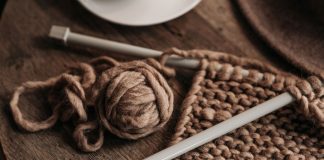 Summer Nights, Yarn, and Park Movies: Your Hudson County Week Ahead A close-up shot of cozy brown yarn and needles on a wooden table, showcasing knitting in progress.
