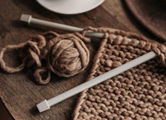 A close-up shot of cozy brown yarn and needles on a wooden table, showcasing knitting in progress.