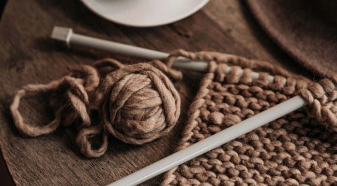 A close-up shot of cozy brown yarn and needles on a wooden table, showcasing knitting in progress.