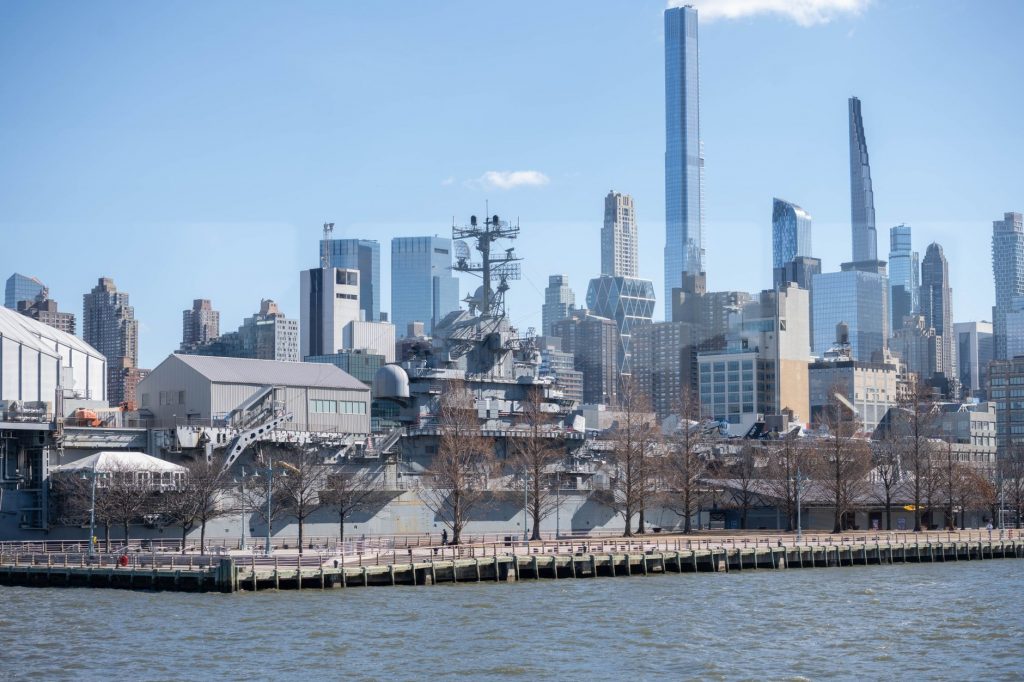 USS Intrepid museum ship with NYC skyscrapers in the background.