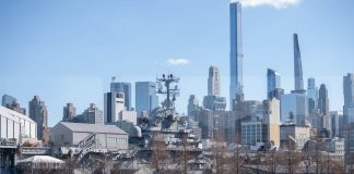 USS Intrepid museum ship with NYC skyscrapers in the background.